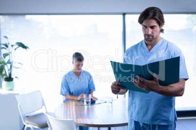 Male surgeon standing in clinic with medical report at hospital