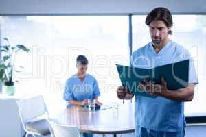Male surgeon standing in clinic with medical report at hospital