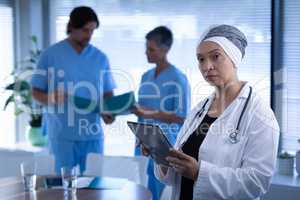 Matured female doctor standing in clinic while holding digital tablet