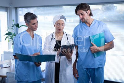 Surgeons discussing over digital tablet in clinic at hospital