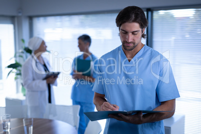 Confident male surgeon writing in medical report in clinic at hospital