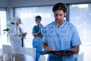 Confident male surgeon writing in medical report in clinic at hospital