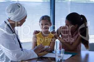 Matured female doctor interacting and examining girl hand in clinic