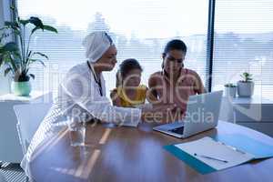 Matured female doctor discussing over laptop with patient in clinic