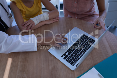 Matured female doctor discussing over laptop with patient in clinic