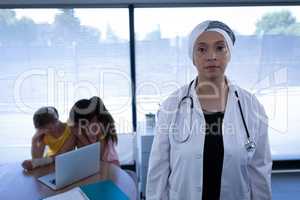 Matured female doctor standing in clinic while mother and doctor sitting upset