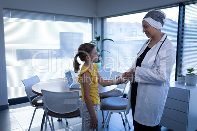 Matured female doctor interacting and examining girl hand in clinic