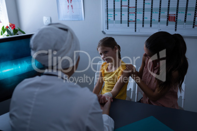 Matured female doctor examining girl hand in clinic