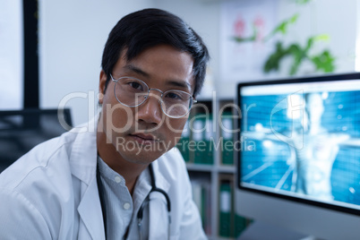 Confident male doctor sitting in clinic at hospital