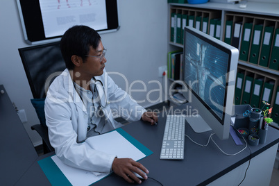 Confident male doctor working on computer in clinic