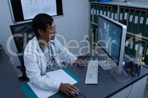 Confident male doctor working on computer in clinic