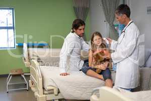 Matured female doctor using otoscope for checking girl ear at hospital