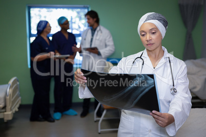 Matured female doctor looking at x-ray report in clinic at hospital