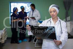 Matured female doctor looking at x-ray report in clinic at hospital