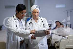 Doctors discussing over digital tablet in clinic at hospital