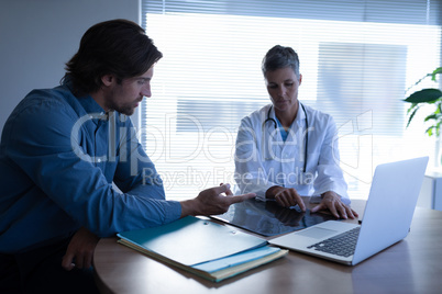 Mature female doctor and patient discussing over x-ray