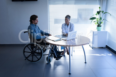 Mature female doctor and patient discussing over laptop