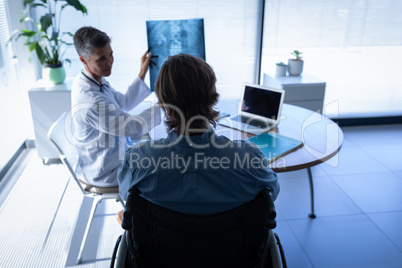 Mature female doctor showing x-ray report to patient in clinic