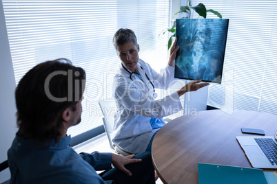 Mature female doctor showing x-ray report to patient in clinic