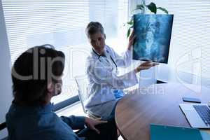 Mature female doctor showing x-ray report to patient in clinic