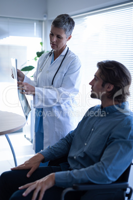 Mature female doctor showing x-ray report to patient in clinic