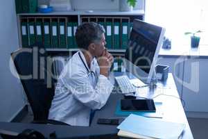 Thoughtful female doctor looking at computer in clinic at hospital