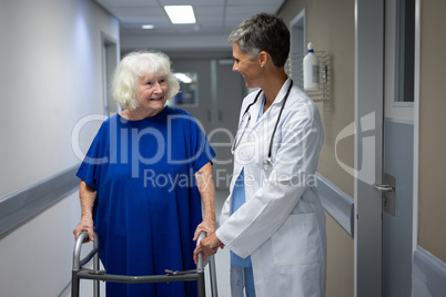 Mature female doctor talking with senior female patient in clinic at hospital