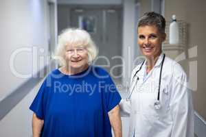 Mature female doctor and senior female patient standing in hospital clinic