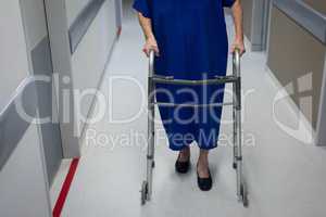 Senior female patient walking with walker in clinic