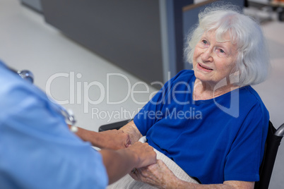 Senior female patient holding hands of surgeon in hospital corridor