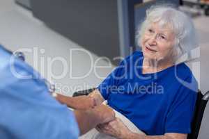Senior female patient holding hands of surgeon in hospital corridor