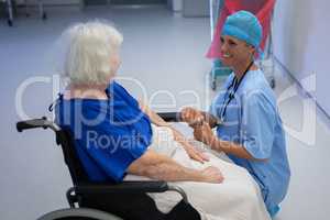 Female surgeon talking with senior female patient in hospital corridor