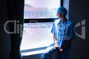 Female surgeon looking outside the through window in clinic