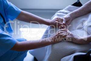 Senior female patient holding hands of surgeon in hospital corridor