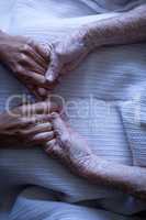 Senior female patient holding hands of surgeon in hospital corridor