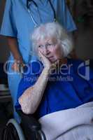 Surgeon pushing the wheelchair of a sad senior female patient