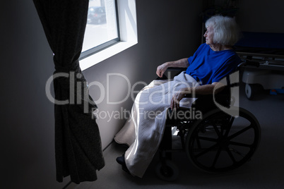 Senior female patient looking outside the window at hospital room