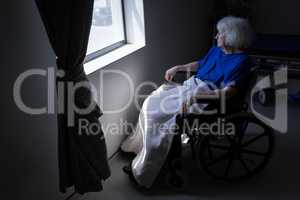 Senior female patient looking outside the window at hospital room