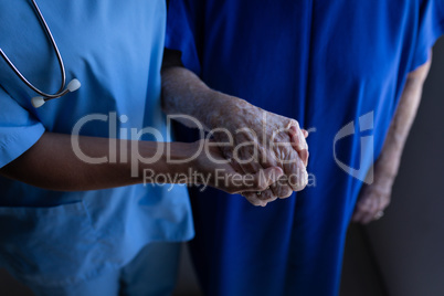 Female surgeon holding hand of senior female patient in clinic