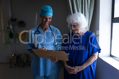 Female surgeon showing a medical report to a senior female patient in a hospital room