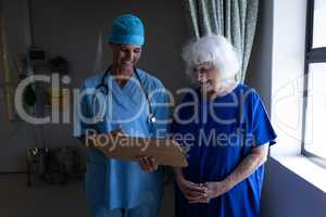 Female surgeon showing a medical report to a senior female patient in a hospital room