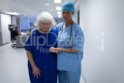 Female surgeon helping senior female patient to cross the hospital corridor