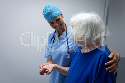 Female surgeon helping a senior patient to walk through the hospital corridor