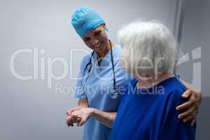 Female surgeon helping a senior patient to walk through the hospital corridor