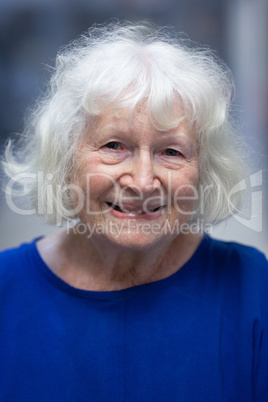 Senior female patient smiling while standing in hospital corridor