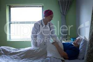 Female doctor talking with senior patient in hospital room
