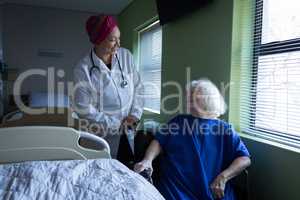 Female doctor talking with senior patient in hospital room