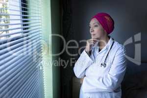 Female doctor looking outside through the window