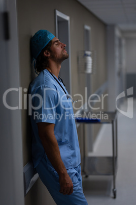 Male surgeon leaning at hospital corridor