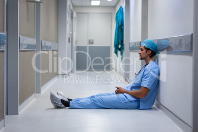 Male surgeon leaning at hospital corridor
